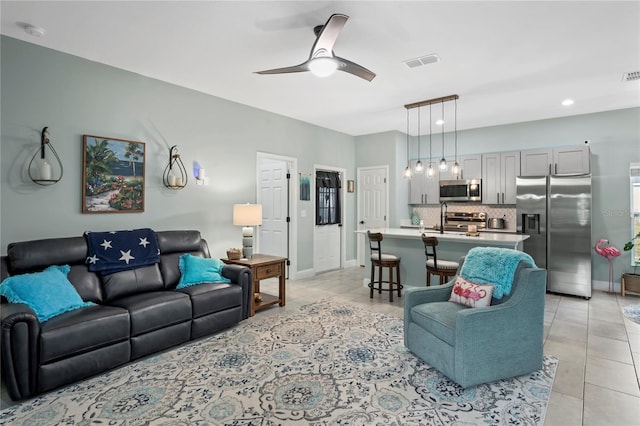 tiled living room with ceiling fan and sink