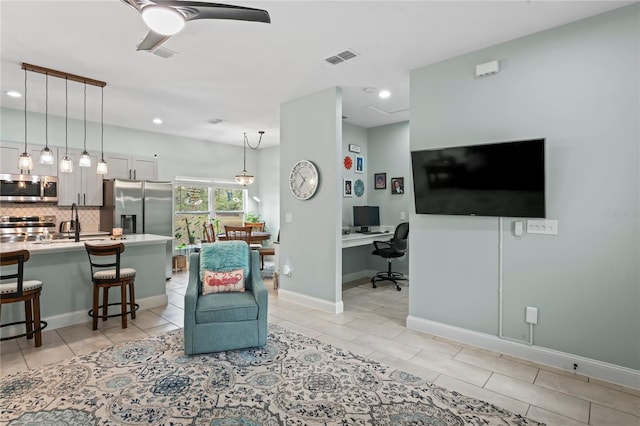 tiled living room featuring ceiling fan and sink