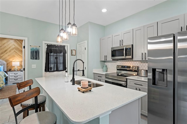 kitchen with appliances with stainless steel finishes, backsplash, a kitchen island with sink, and sink