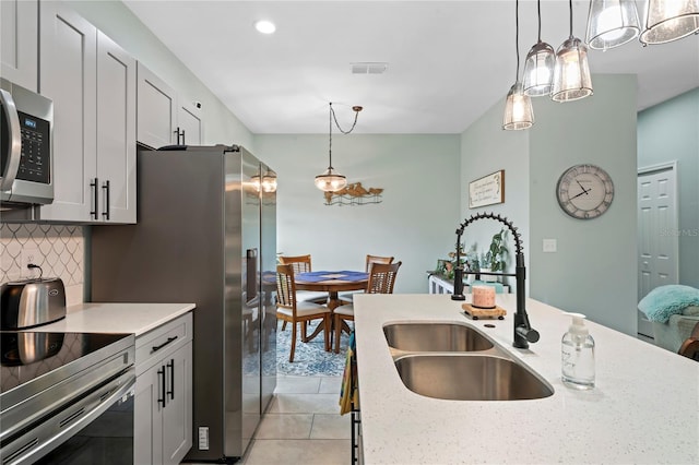 kitchen featuring sink, decorative light fixtures, decorative backsplash, light tile patterned floors, and appliances with stainless steel finishes