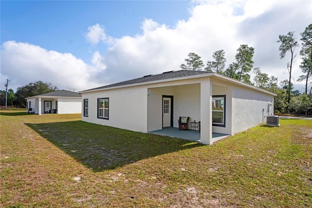 rear view of property featuring central air condition unit, a lawn, and a patio