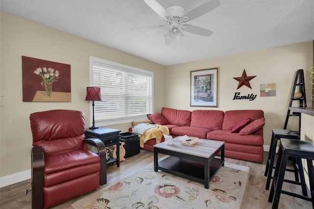 living room featuring ceiling fan, a textured ceiling, and light hardwood / wood-style flooring