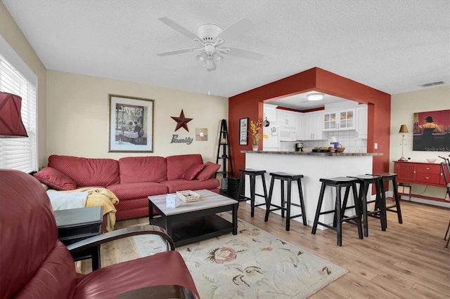 living room featuring a textured ceiling, light hardwood / wood-style flooring, and ceiling fan