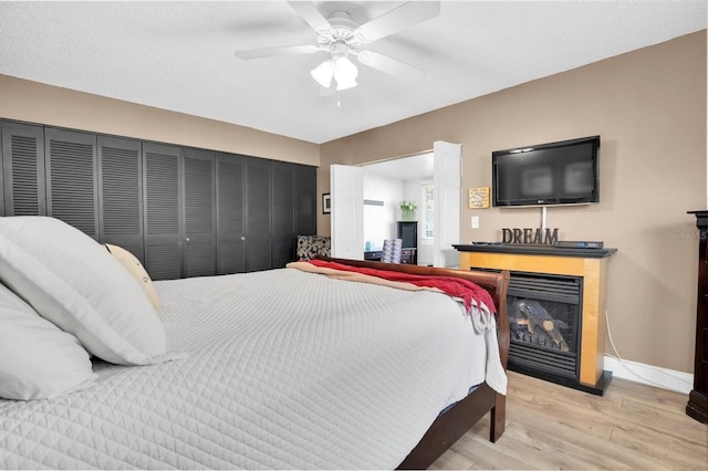 bedroom featuring ceiling fan, a closet, a textured ceiling, and light hardwood / wood-style flooring