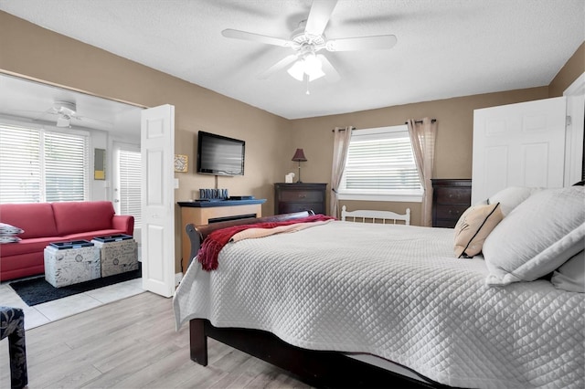 bedroom with multiple windows, ceiling fan, a textured ceiling, and light wood-type flooring