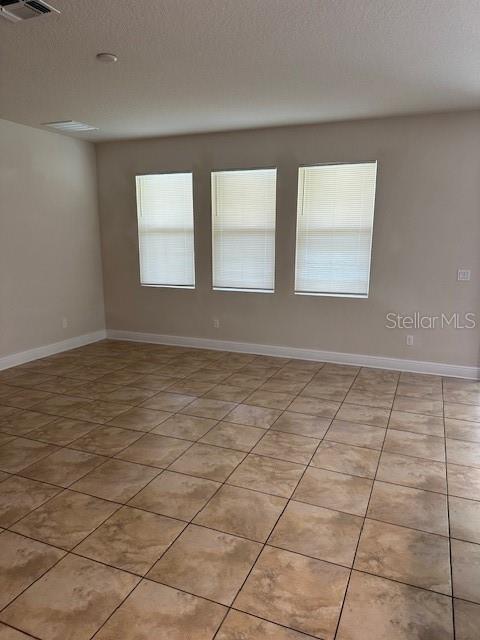 tiled spare room featuring a textured ceiling