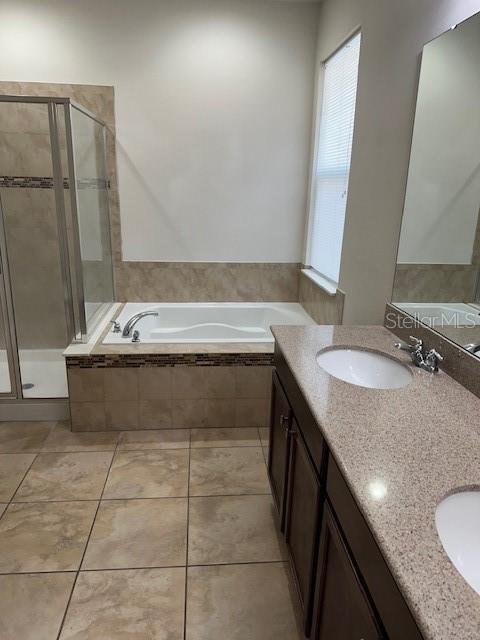 bathroom featuring tile patterned flooring, vanity, and shower with separate bathtub