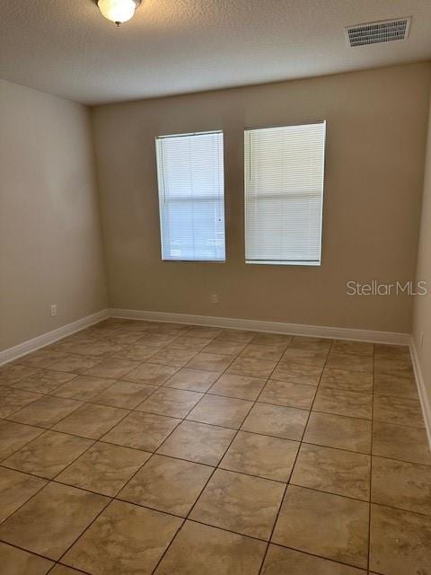 tiled spare room featuring a textured ceiling