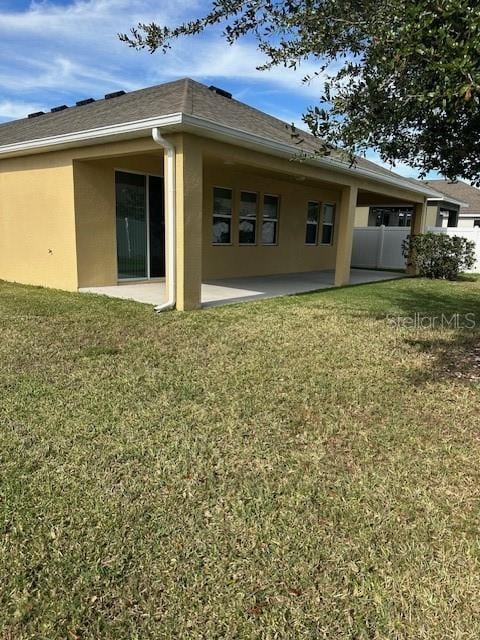 rear view of house with a lawn and a patio