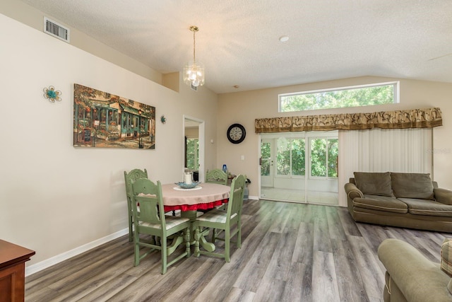 dining area featuring a chandelier, a textured ceiling, hardwood / wood-style flooring, and vaulted ceiling