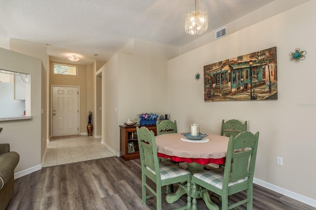 dining area with hardwood / wood-style floors, a notable chandelier, and a textured ceiling