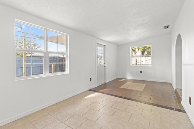 tiled empty room featuring a textured ceiling