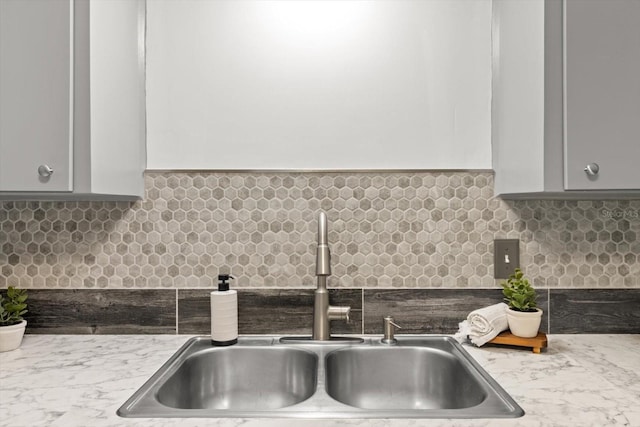 interior details with light stone countertops, tasteful backsplash, and sink