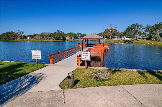 dock area with a gazebo, a yard, and a water view