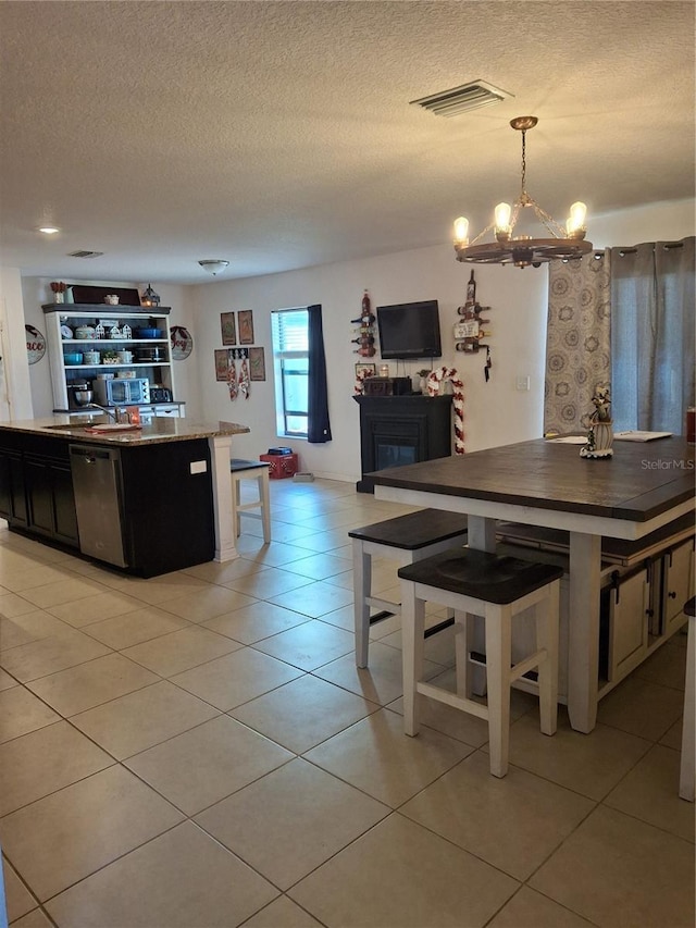 kitchen with pendant lighting, a textured ceiling, light tile patterned floors, and a kitchen breakfast bar