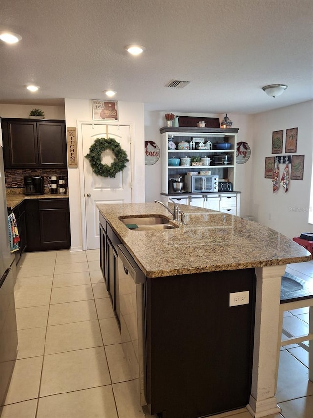 kitchen featuring a kitchen island with sink, sink, dishwasher, and light tile patterned floors