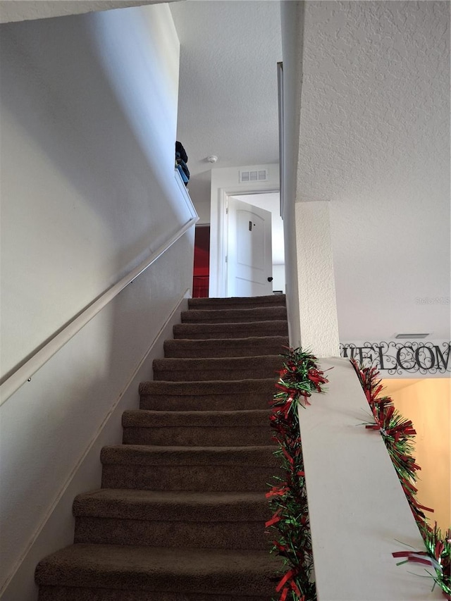 stairs featuring a textured ceiling