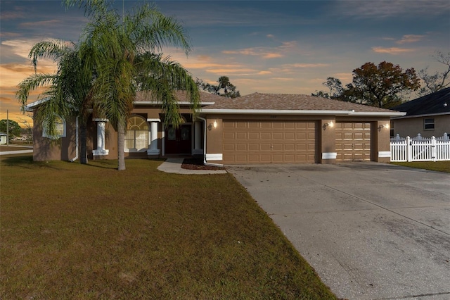 ranch-style home featuring a lawn and a garage