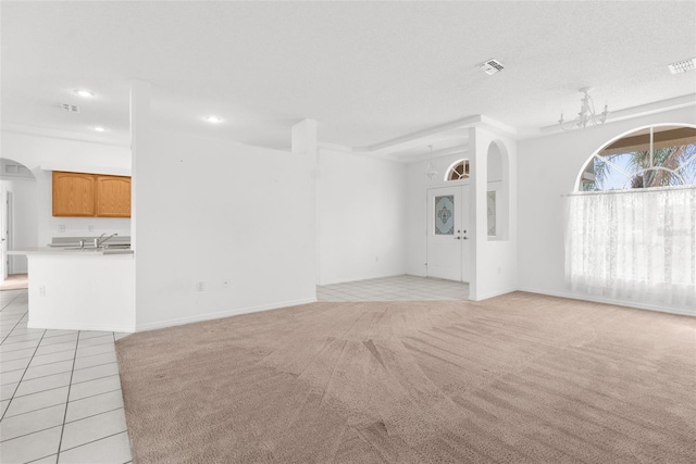 unfurnished living room featuring arched walkways, visible vents, light carpet, a sink, and light tile patterned flooring