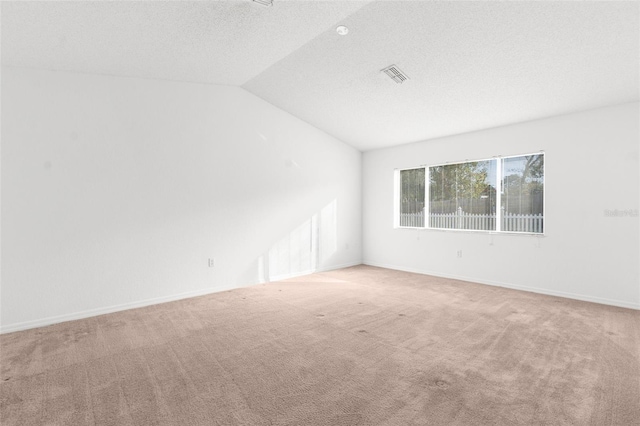 unfurnished room featuring visible vents, vaulted ceiling, a textured ceiling, and carpet flooring