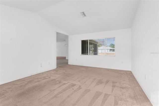 carpeted empty room featuring lofted ceiling and visible vents