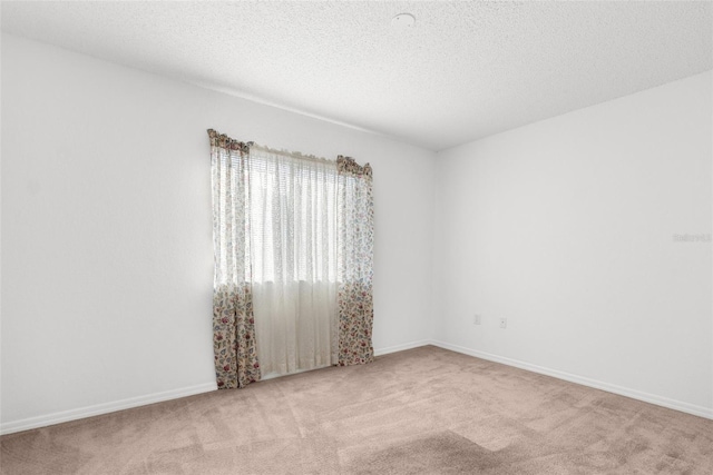 unfurnished room featuring a textured ceiling, carpet flooring, and baseboards