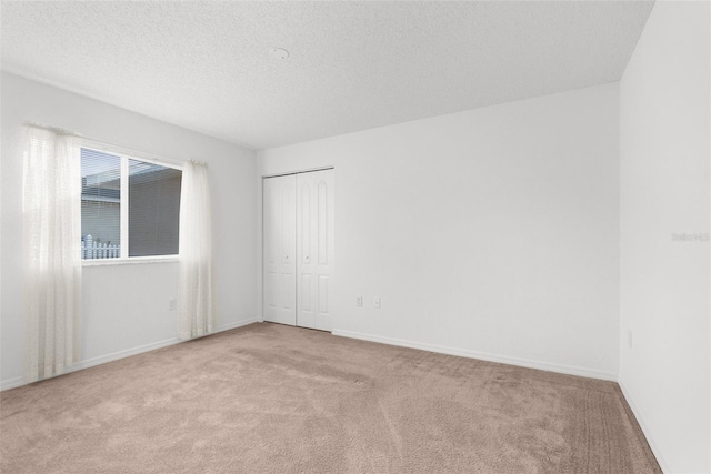 carpeted empty room featuring a textured ceiling