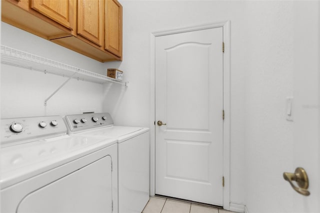 laundry room with cabinet space, light tile patterned floors, and washer and dryer