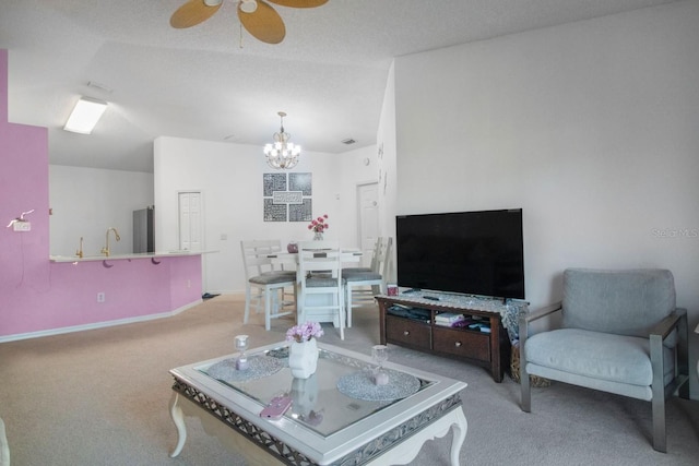 carpeted living room featuring a textured ceiling, ceiling fan with notable chandelier, and vaulted ceiling