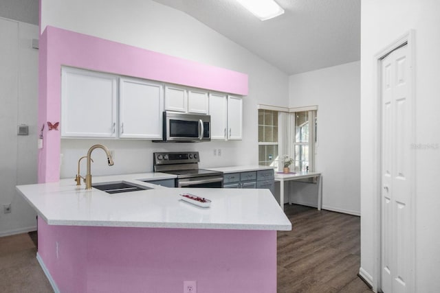 kitchen with kitchen peninsula, appliances with stainless steel finishes, white cabinetry, and lofted ceiling