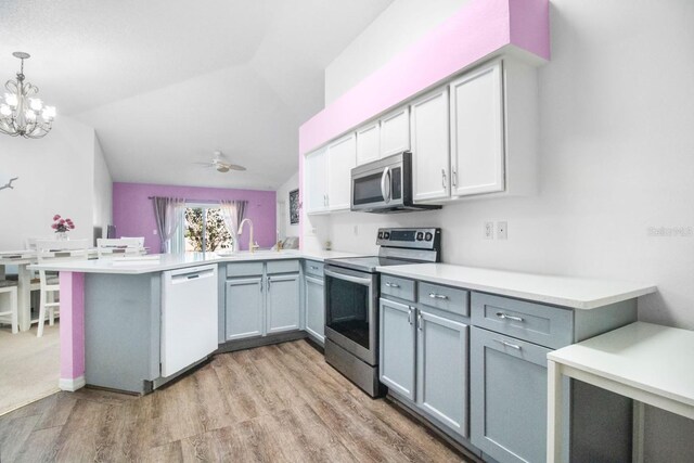 kitchen featuring ceiling fan with notable chandelier, sink, decorative light fixtures, kitchen peninsula, and stainless steel appliances