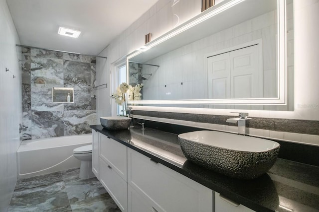 full bathroom with tile walls, vanity, tiled shower / bath combo, and toilet