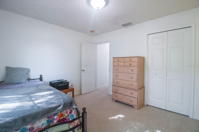 carpeted bedroom featuring a textured ceiling and a closet