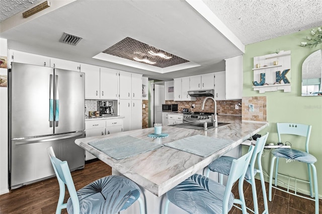 kitchen with white cabinets, kitchen peninsula, appliances with stainless steel finishes, and tasteful backsplash