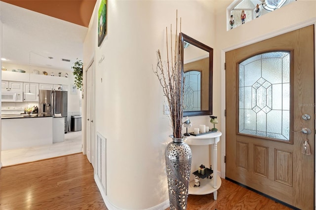 foyer with a high ceiling, a healthy amount of sunlight, and light wood-type flooring