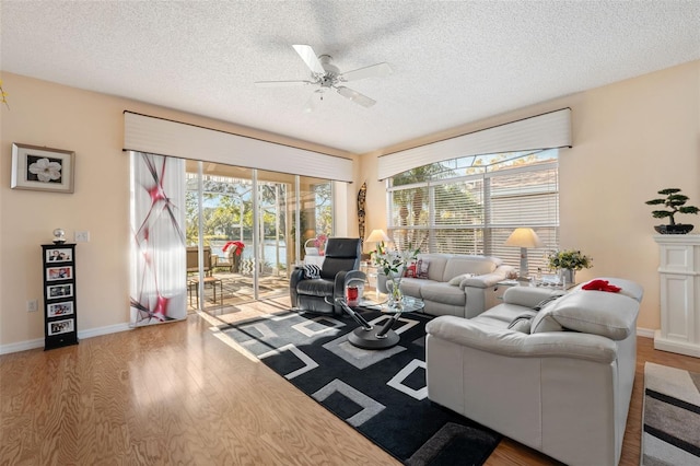 living room featuring hardwood / wood-style flooring, ceiling fan, and a textured ceiling