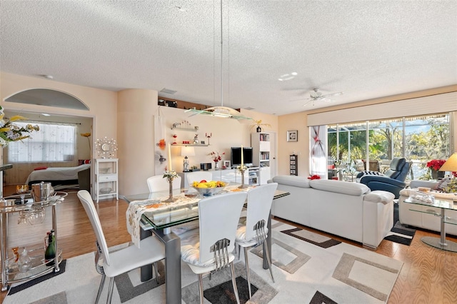 dining space with ceiling fan, light hardwood / wood-style flooring, and a textured ceiling