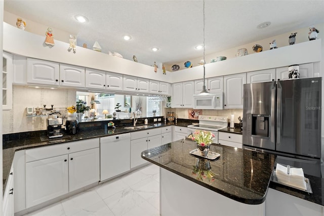 kitchen with white appliances, dark stone counters, sink, and white cabinets