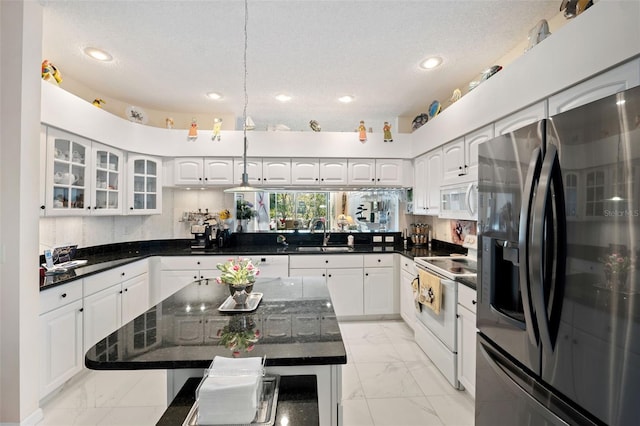 kitchen with sink, a kitchen island, pendant lighting, stainless steel appliances, and white cabinets