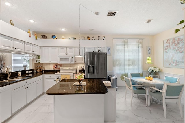 kitchen with sink, white cabinetry, a center island, hanging light fixtures, and white appliances