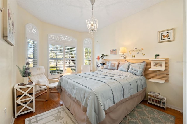 bedroom featuring hardwood / wood-style floors, a notable chandelier, and a textured ceiling