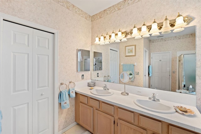 bathroom with a shower with door, vanity, and tile patterned flooring