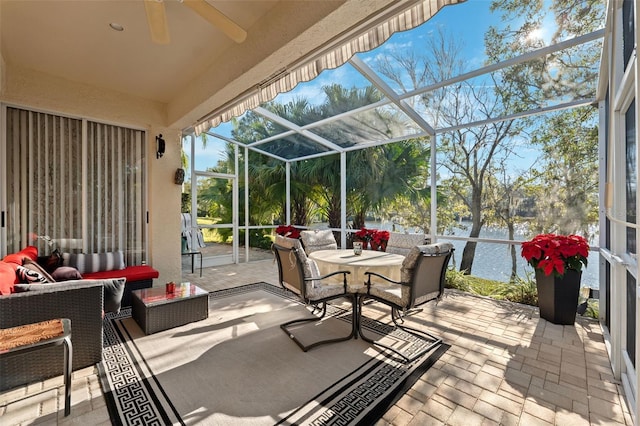 sunroom featuring a water view and ceiling fan