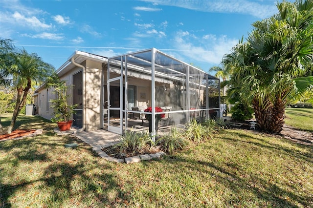 rear view of house with a lanai, central AC unit, and a lawn