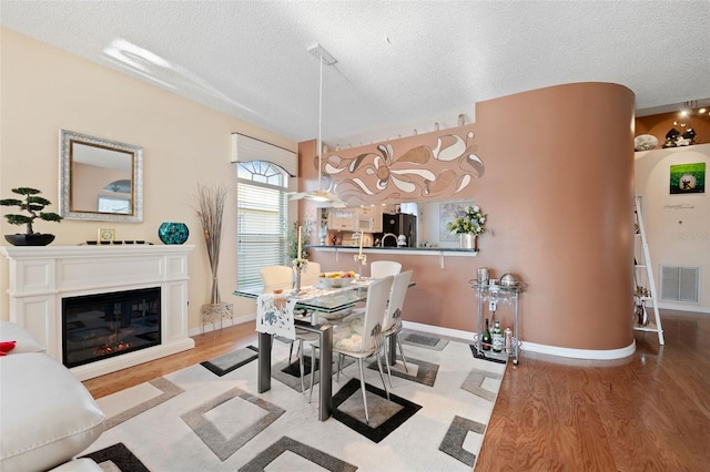 dining space featuring light hardwood / wood-style floors and a textured ceiling