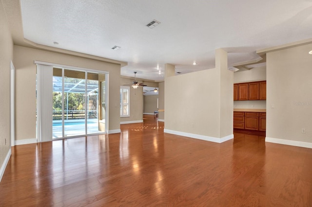 unfurnished living room with ceiling fan, hardwood / wood-style floors, and a textured ceiling