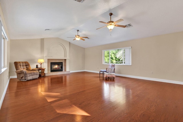 unfurnished living room featuring hardwood / wood-style flooring, ceiling fan, vaulted ceiling, and a tile fireplace