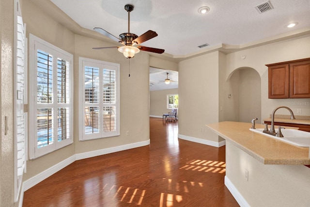 kitchen featuring ceiling fan, a breakfast bar, dark hardwood / wood-style flooring, and sink