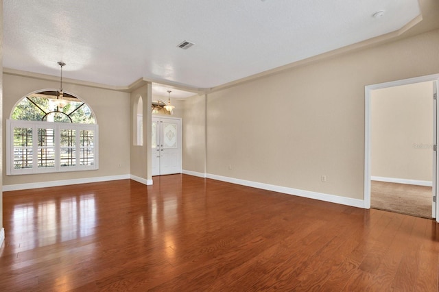 unfurnished living room with a textured ceiling, a notable chandelier, and dark hardwood / wood-style floors