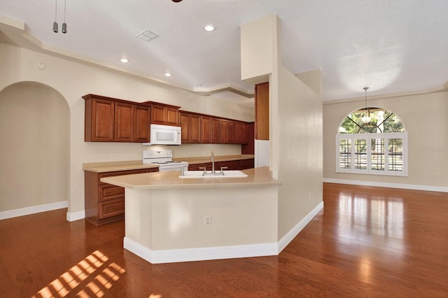 kitchen with white appliances, dark hardwood / wood-style floors, pendant lighting, and sink